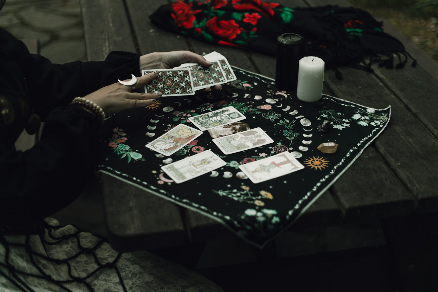 Händer som håller tarotkort omgivna av ljus och kristaller.